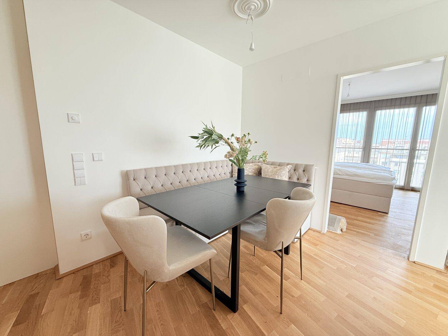 Heller Essbereich mit gepolsterter Sitzbank, modernem Tisch und Parkettboden.
