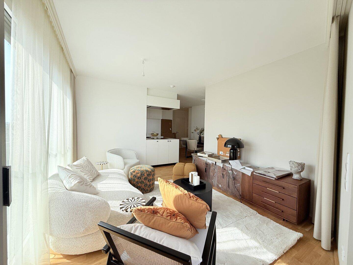 Heller Wohnbereich mit modernem Sofa, Parkettboden und Blick in den Essbereich.