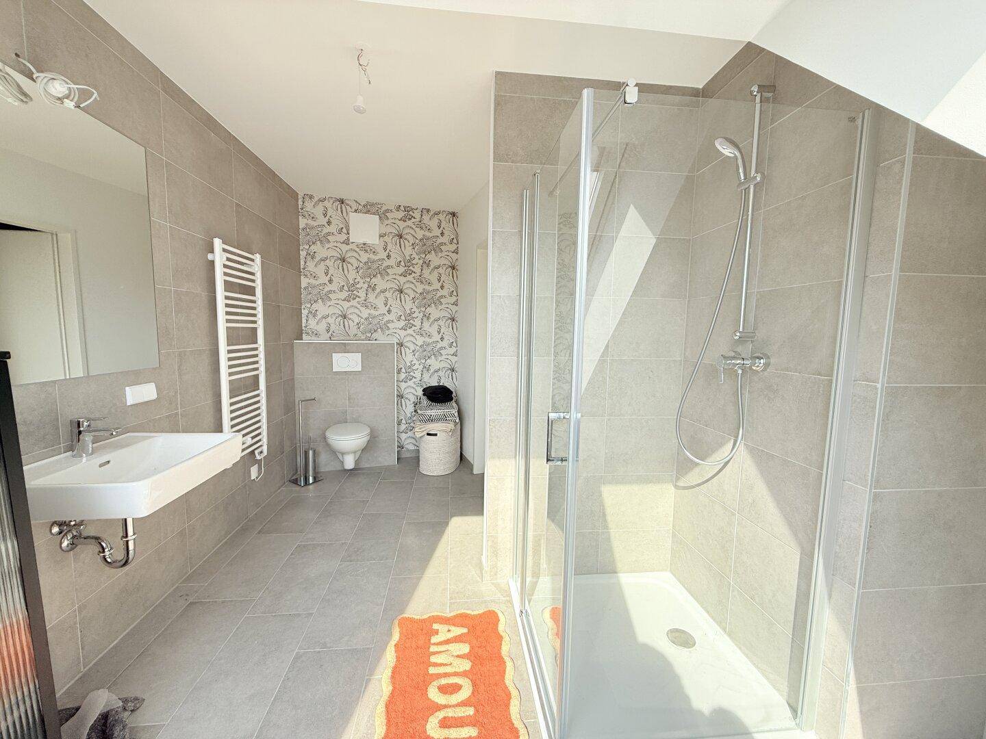 Geräumiges Badezimmer mit moderner Dusche, Wand-WC und hellen Fliesen.