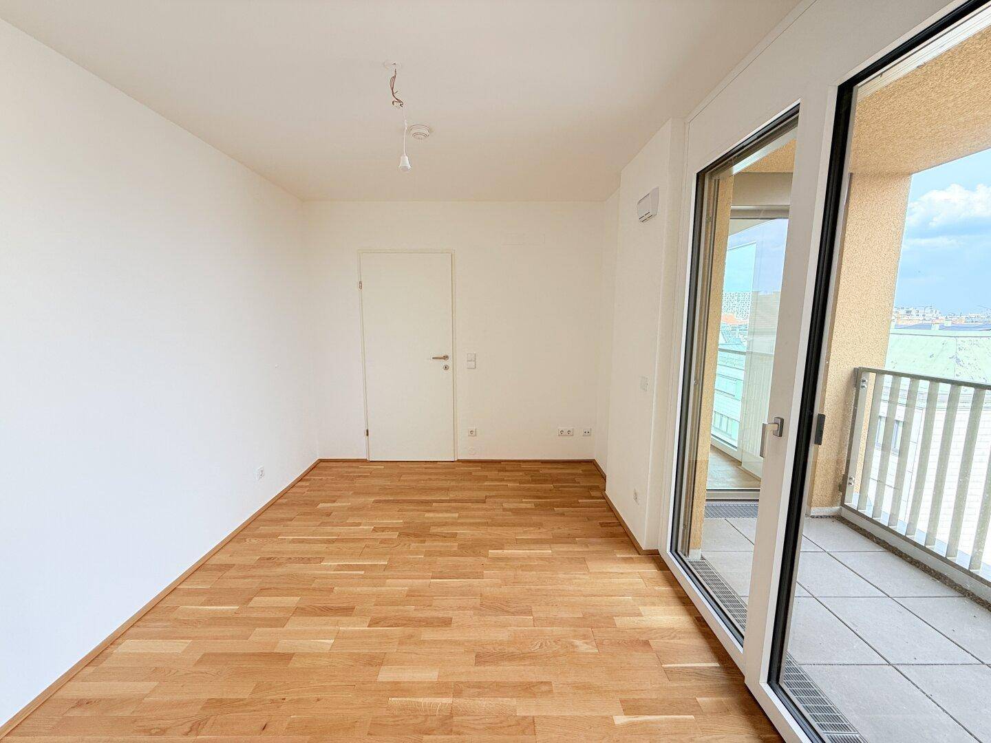 Helles Schlafzimmer mit Parkettboden und Balkonzugang, ideal für viel Tageslicht.