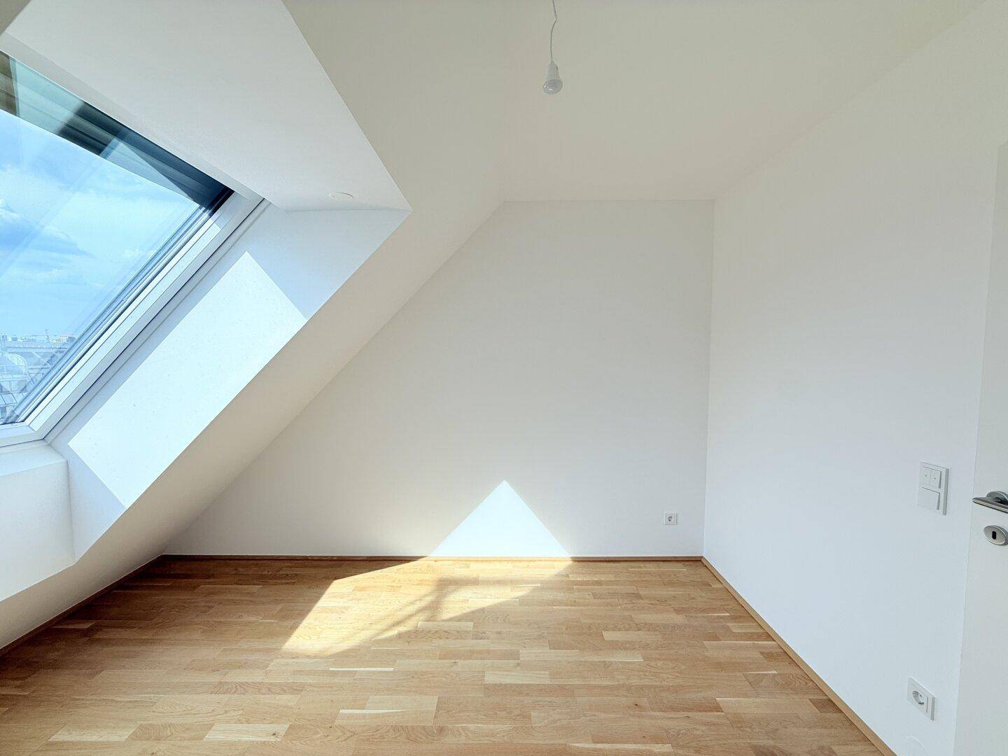 Gemütliches Schlafzimmer im Dachgeschoss mit schrägem Dachfenster und viel Sonnenlicht, modern.