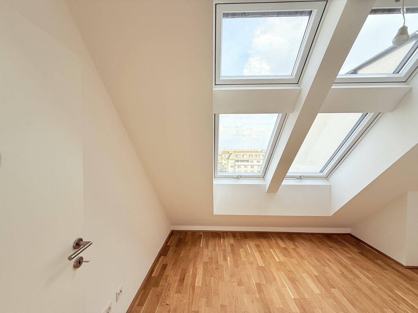Helles Dachgeschosszimmer mit mehreren Dachfenstern und Blick auf die Umgebung, vielseitig nutzbar.