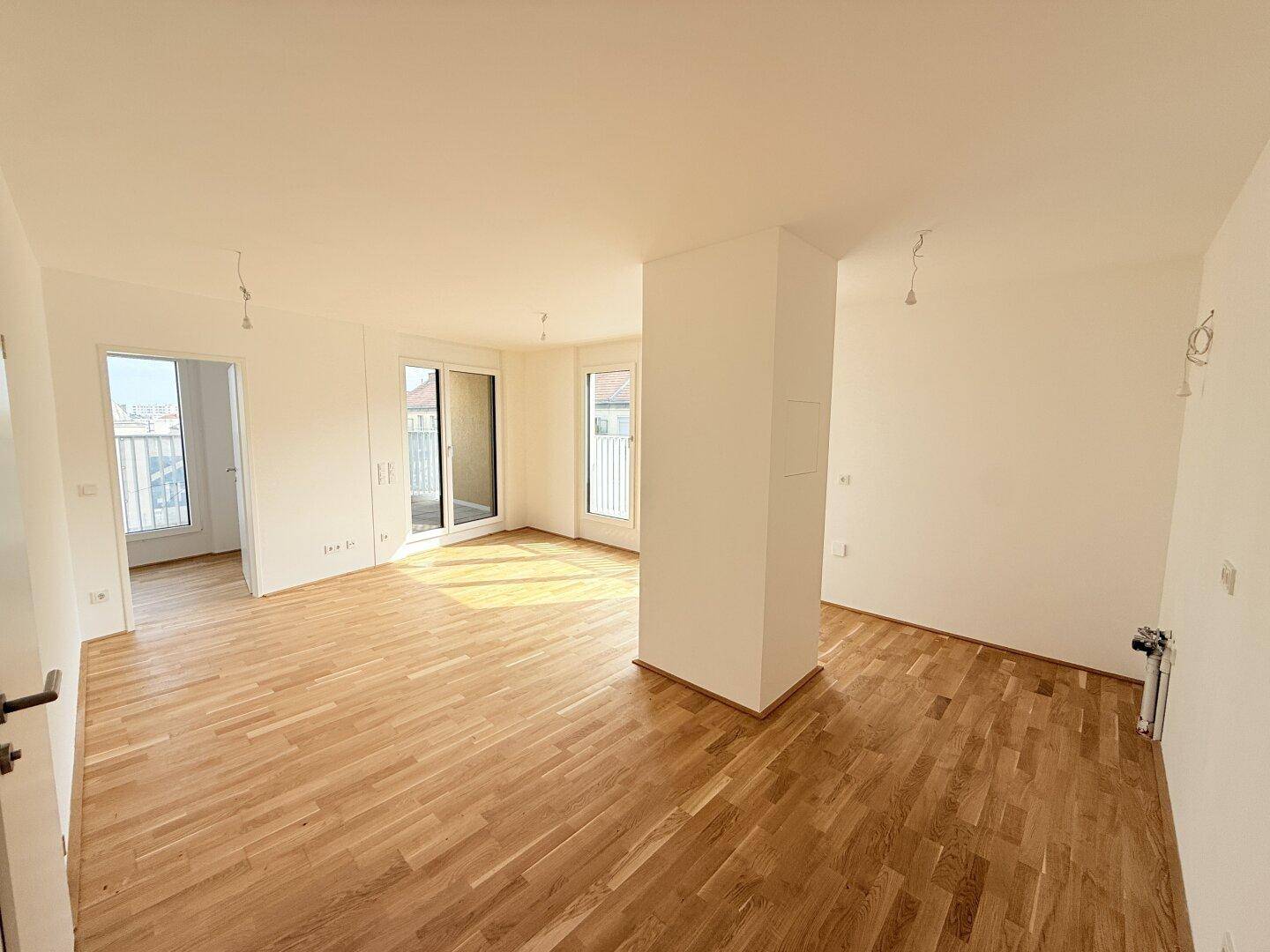 Geräumiges, helles Wohnzimmer mit Parkettboden und mehreren Fenstern, bereit zur Einrichtung.