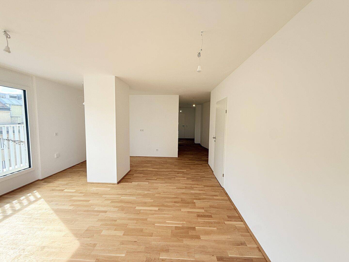 Heller Wohnbereich mit Parkettboden und Blick in den Flur, ideal für offenes Wohnen.