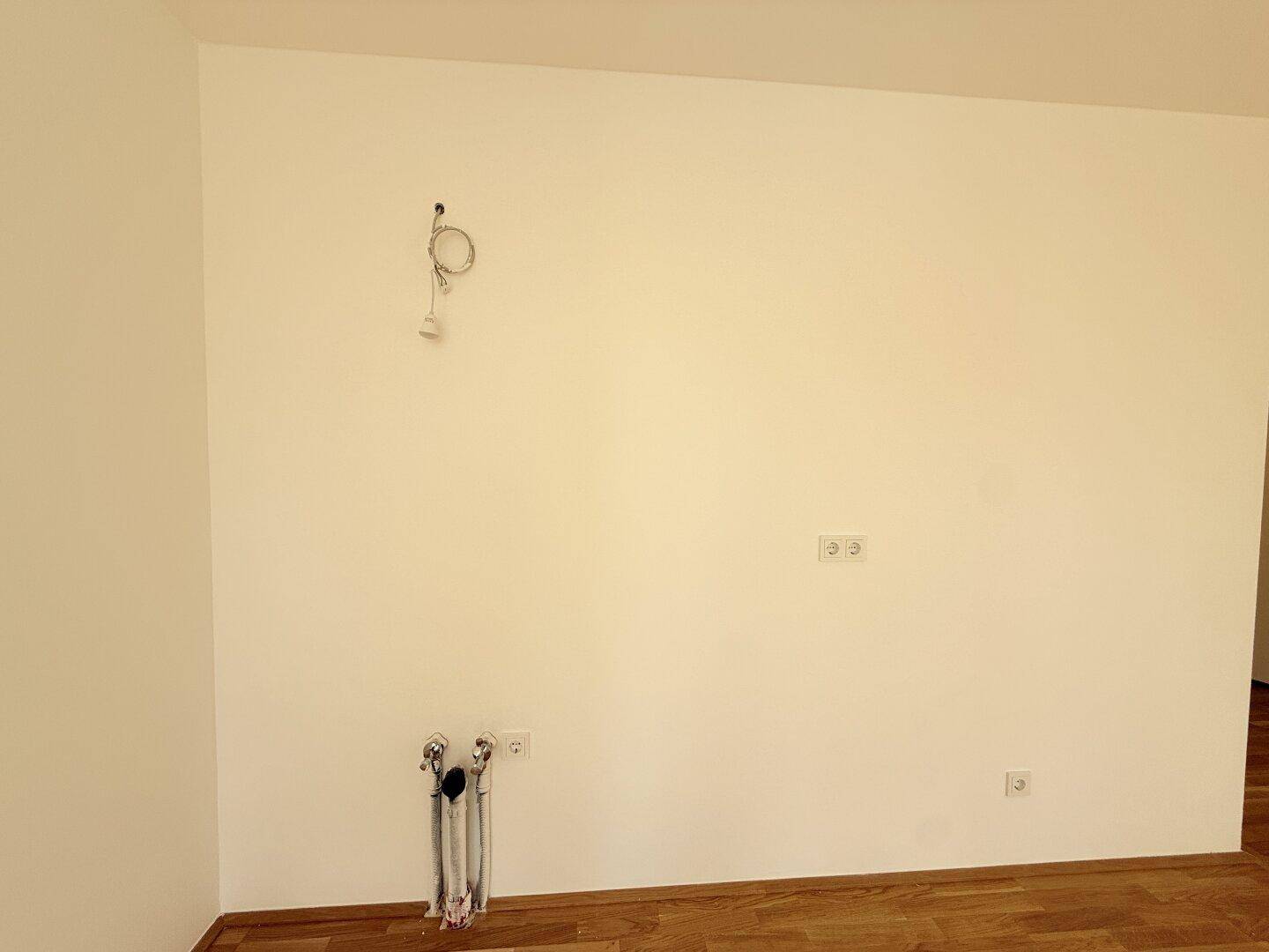 Wandbereich für die zukünftige Küche mit vorbereiteten Anschlüssen und Steckdosen.