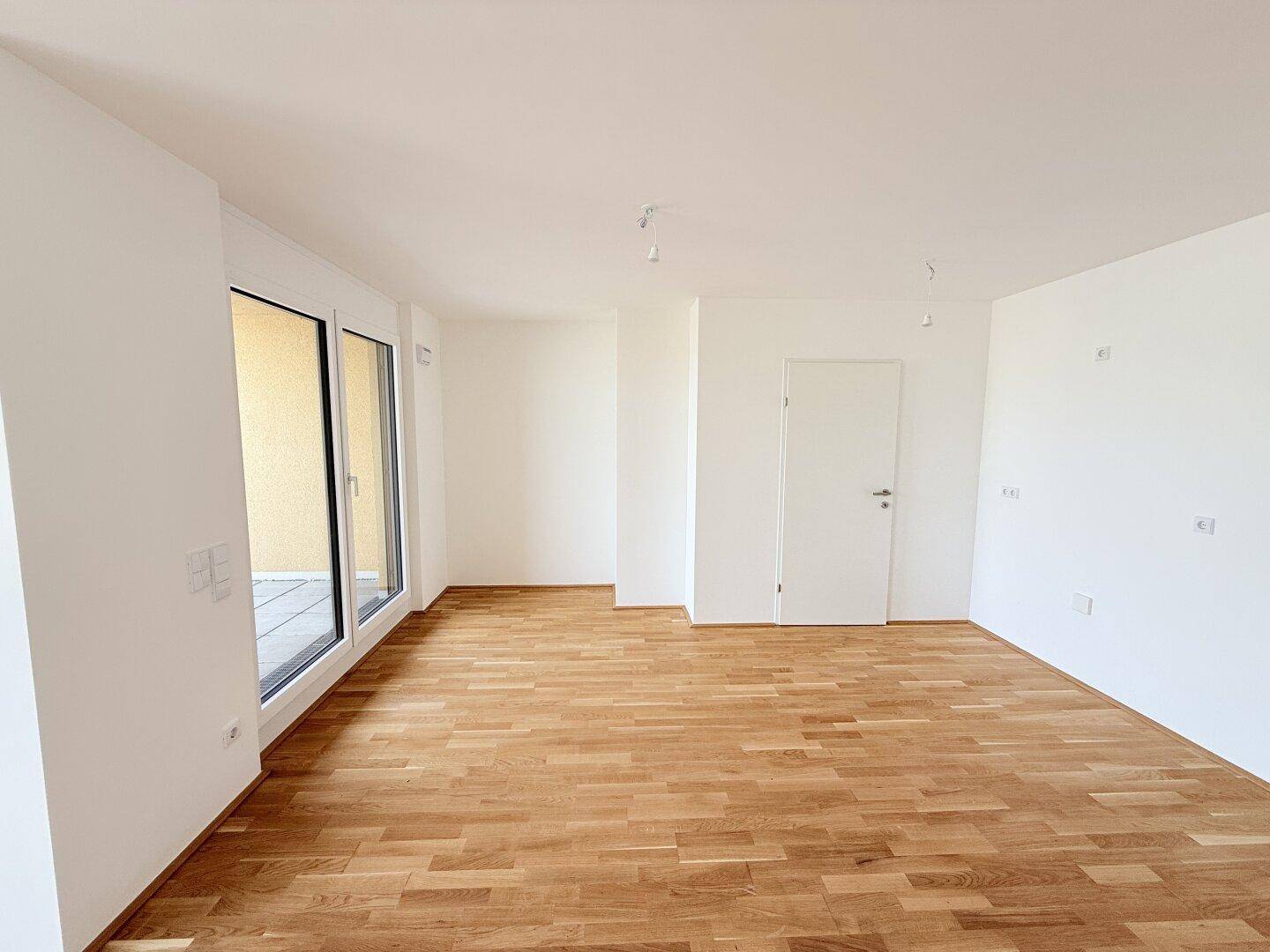 Geräumiger, heller Wohnbereich mit Parkettboden und großen Fenstern, ideal für offenes Wohnen.