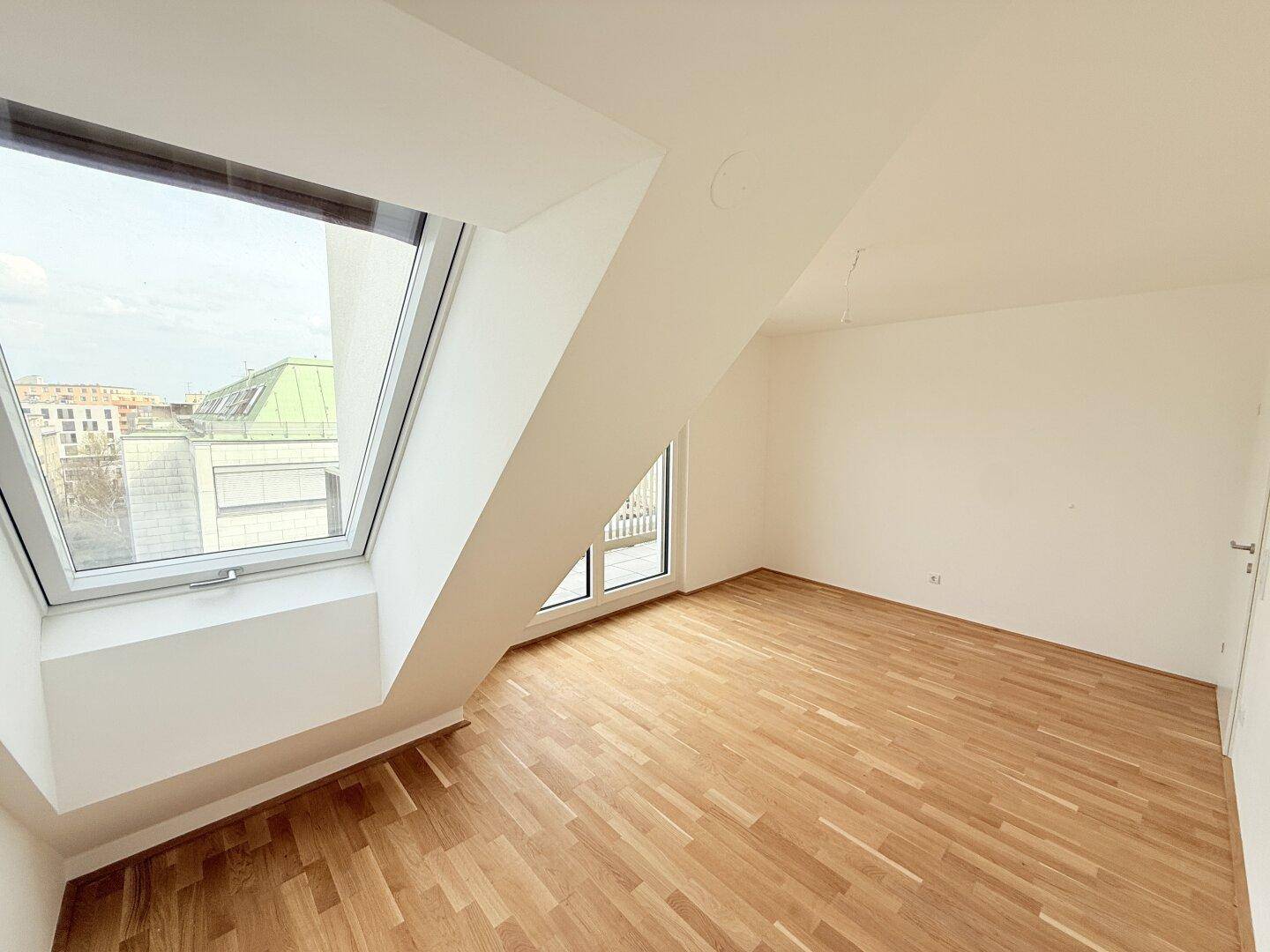 Helles Schlafzimmer mit Parkettboden, Dachschräge und großem Dachfenster.