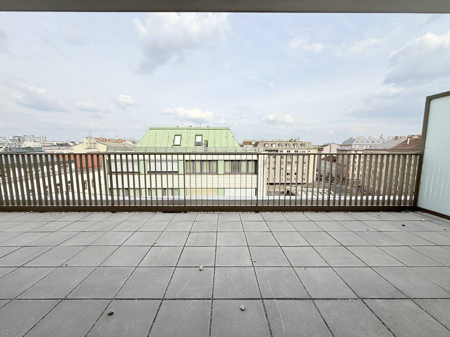 Weitläufige Dachterrasse mit Fliesenboden und Metallgeländer, bietet Stadtblick.