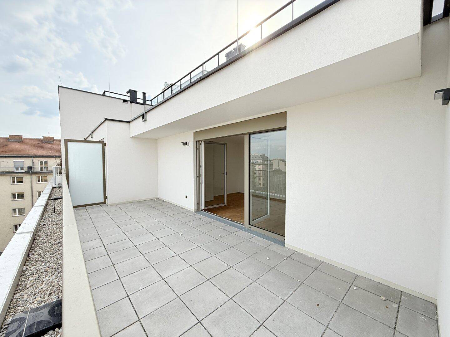 Geräumige Dachterrasse mit Fliesenboden und Zugang zu den Innenräumen.