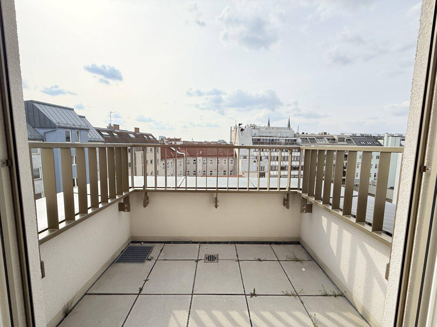 Geräumiger Balkon mit Fliesenboden und Blick auf die Stadt, ideal für entspannte Stunden.