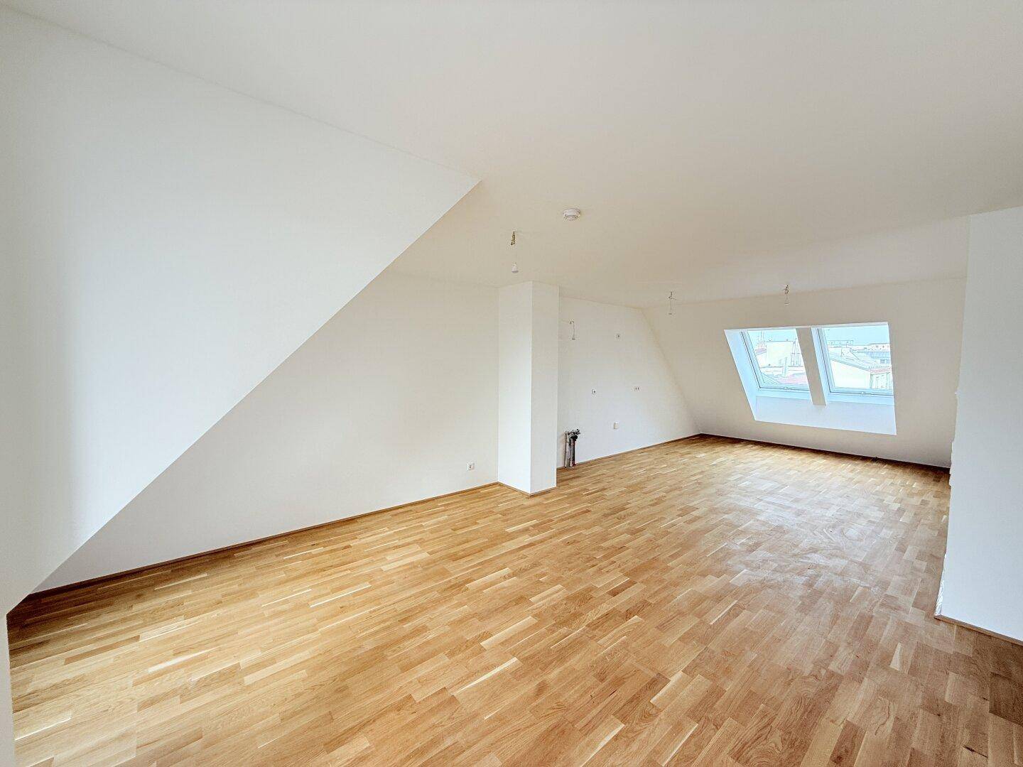 Großzügiger Dachgeschossraum mit Parkettboden und schrägen Wänden, bietet viel Gestaltungspotenzial.