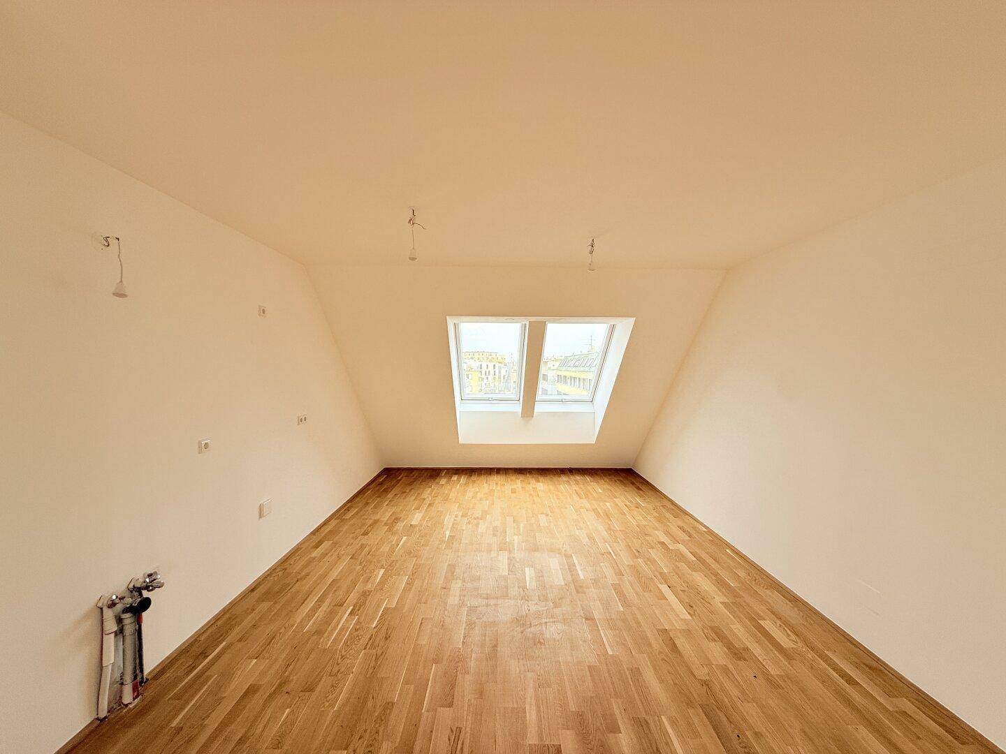 Lichtdurchfluteter Dachraum mit zwei Dachfenstern und neuem Parkettboden, ideal für Wohnzwecke.