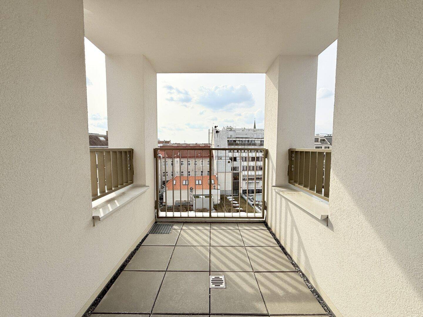 Kleiner Balkon mit Fliesenboden und Metallgeländer, bietet einen Blick auf die Stadt.