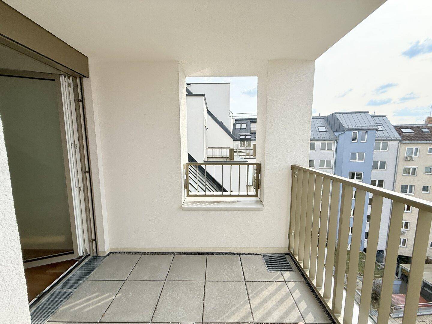 Balkon mit Fliesenboden und Blick auf die umliegenden Gebäude, ideal für Entspannung.