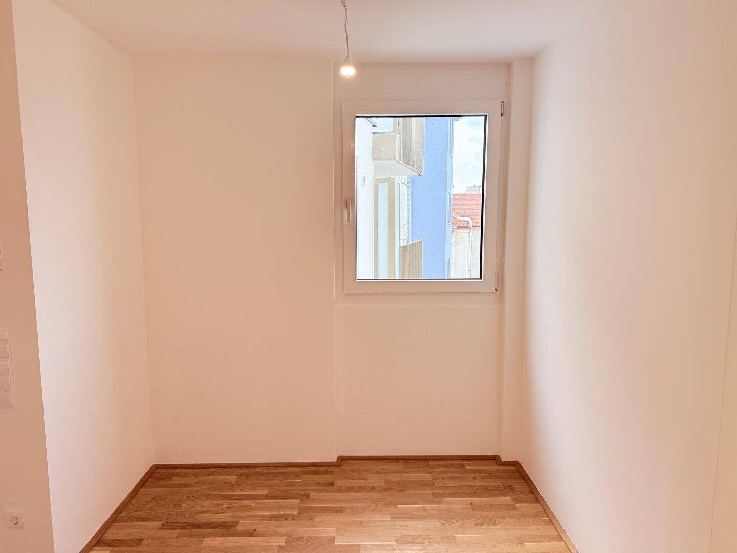 Schlafzimmer mit Parkettboden und einem Fenster, das für ausreichend Helligkeit sorgt.