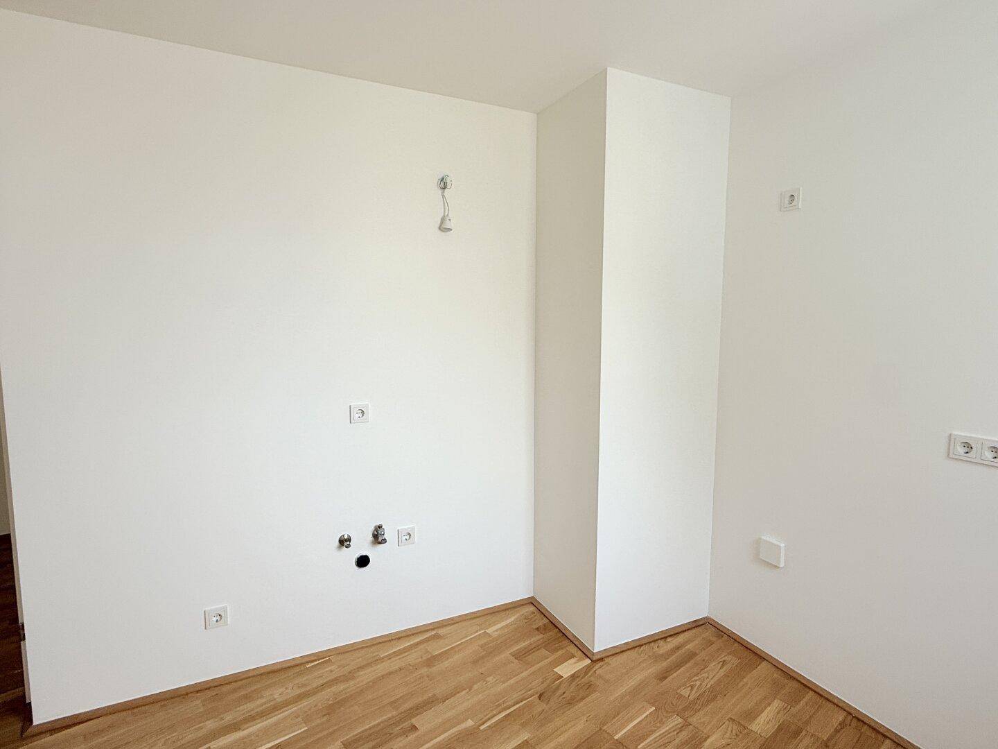 Unmöblierter Küchenraum mit allen notwendigen Anschlüssen für eine moderne Küche.