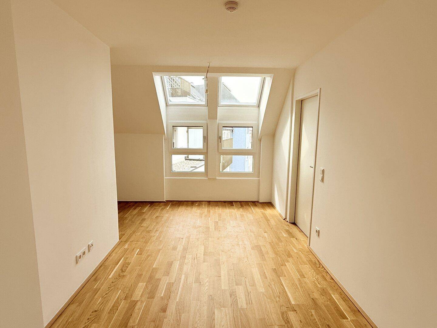 Lichtdurchfluteter Raum im Dachgeschoss mit mehreren Dachfenstern und hellem Parkettboden.