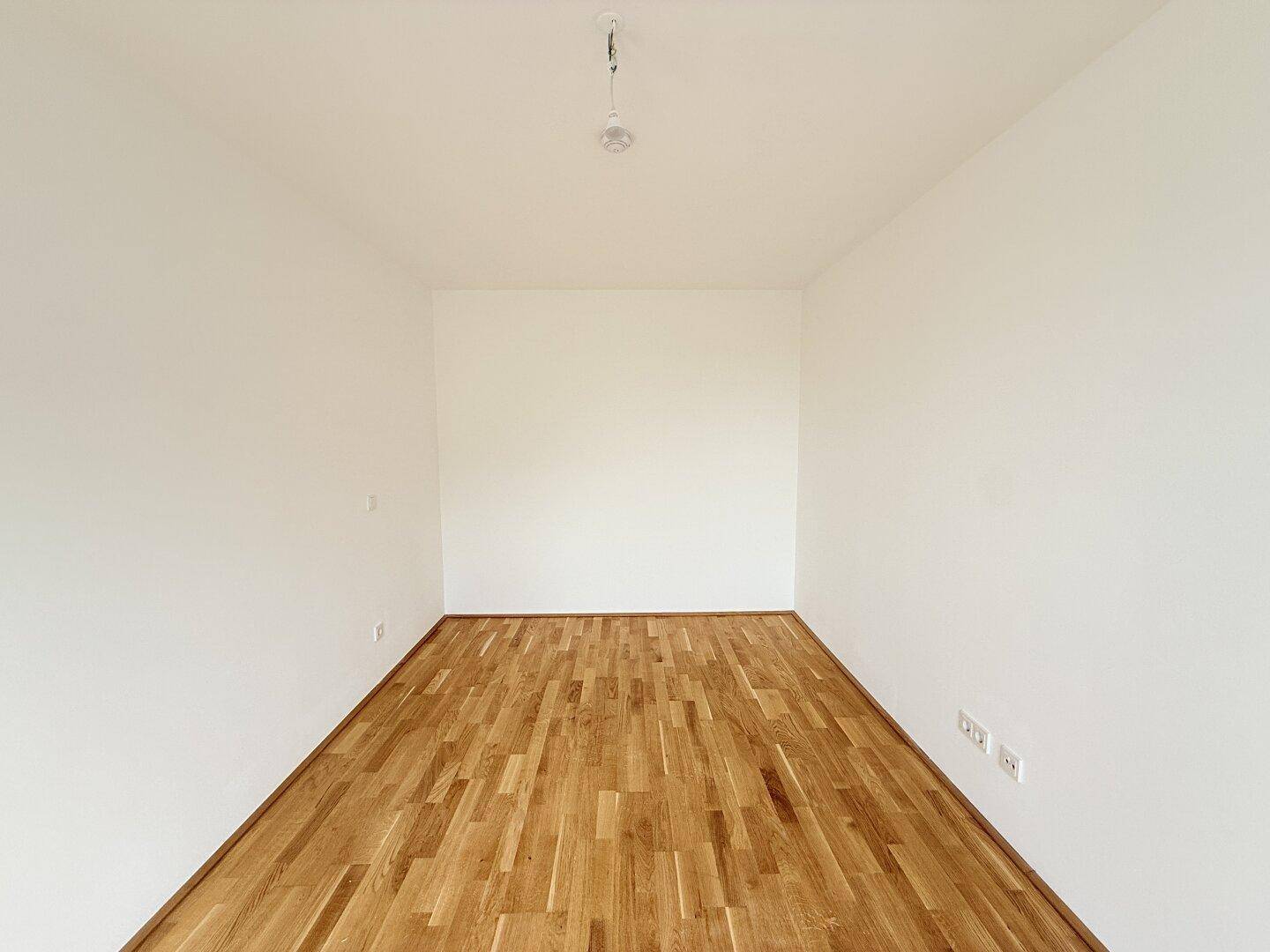 Schlichter, heller Raum mit Parkettboden und weißen Wänden, ideal für individuelle Gestaltung.
