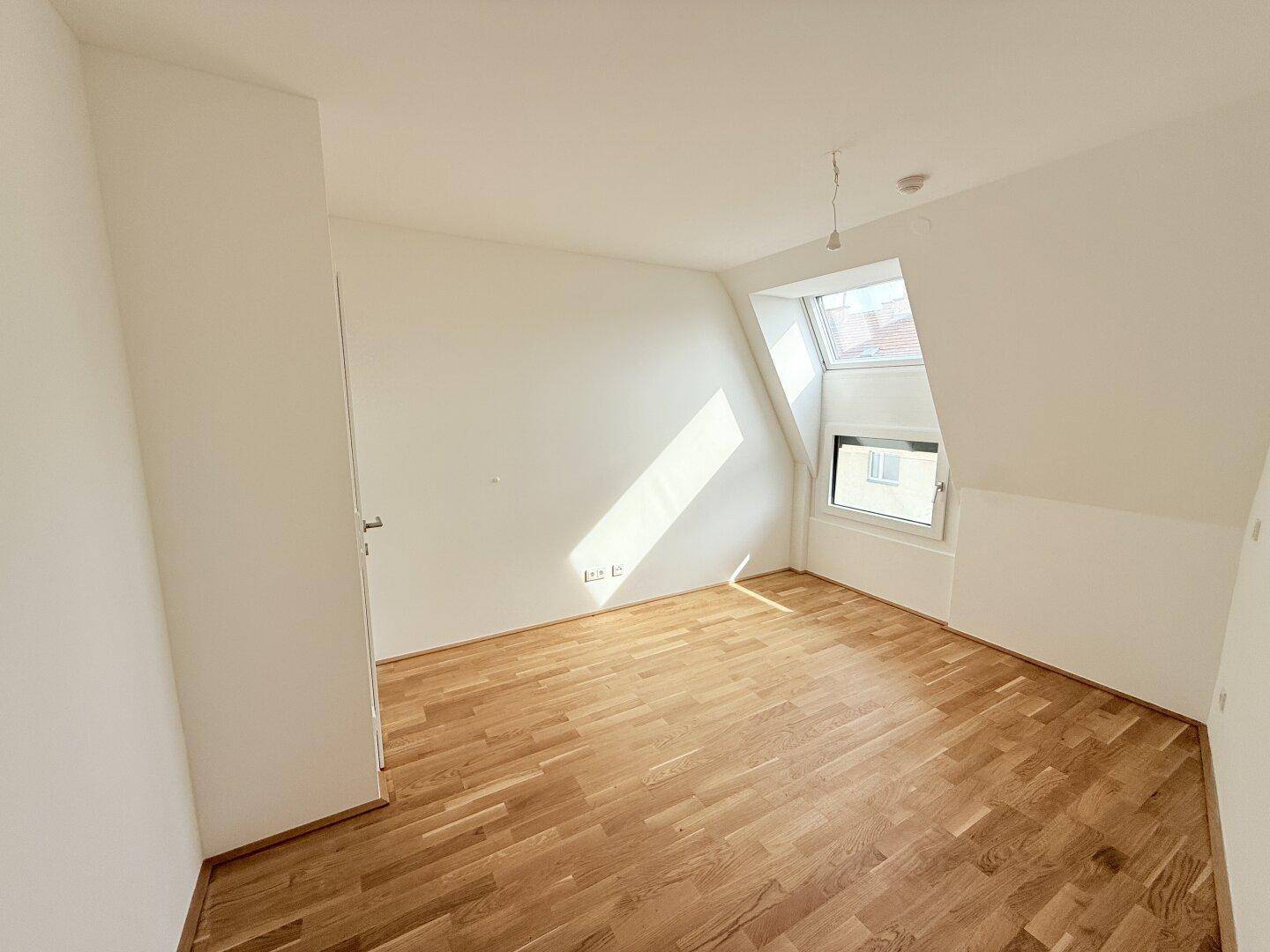 Helles Zimmer im Dachgeschoss mit Parkettboden und Dachfenster, ideal für ein ruhiges Arbeitsumfeld.