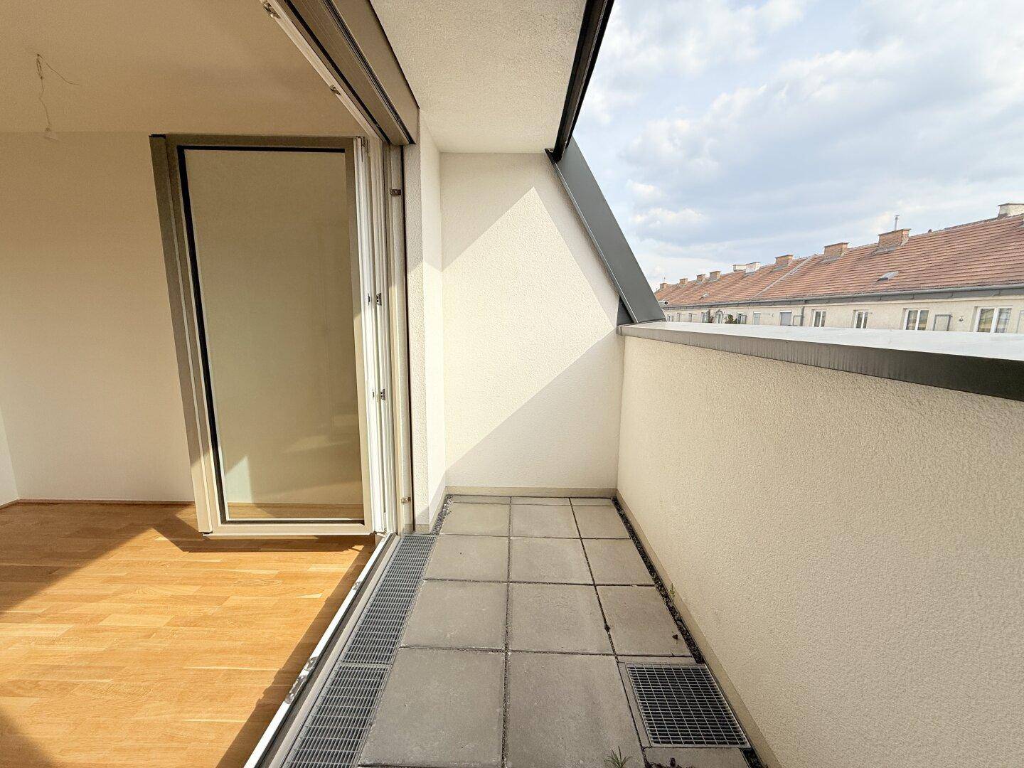 Kleiner Balkon mit Fliesenboden und Blick auf die umliegenden Dächer, zugänglich vom Innenraum.