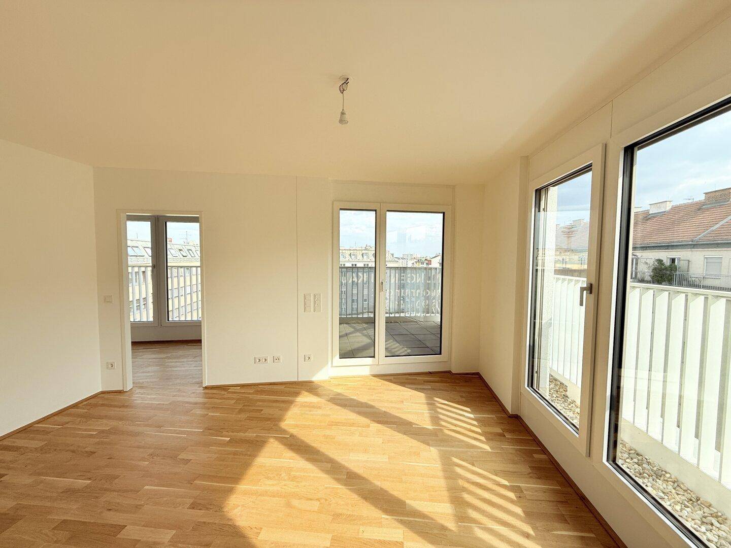 Lichtdurchfluteter Wohnbereich mit Holzboden und Zugang zu einem Balkon, bietet eine offene Atmosphäre.