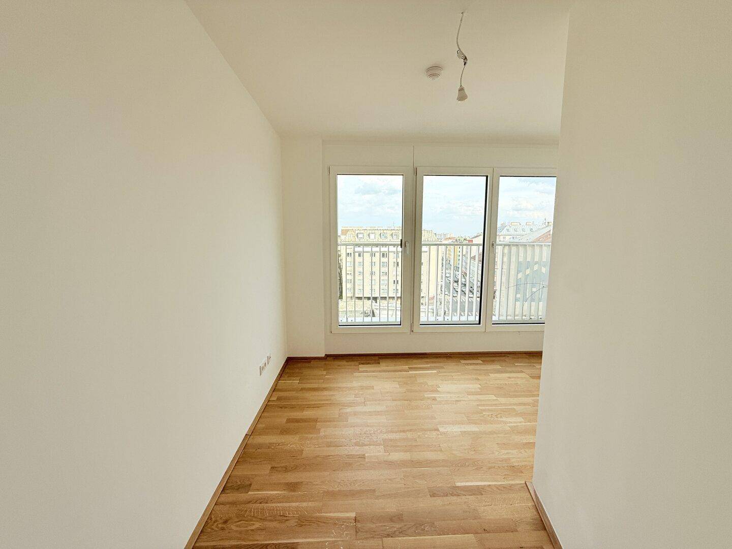 Heller Raum mit Parkettboden und großen Fenstern, ideal als Schlafzimmer oder Arbeitszimmer nutzbar.