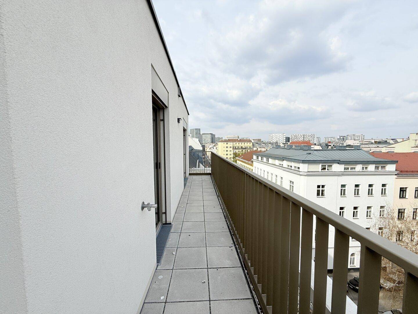 Langer, schmaler Balkon mit Fliesenboden und Blick auf die Stadtstraße.