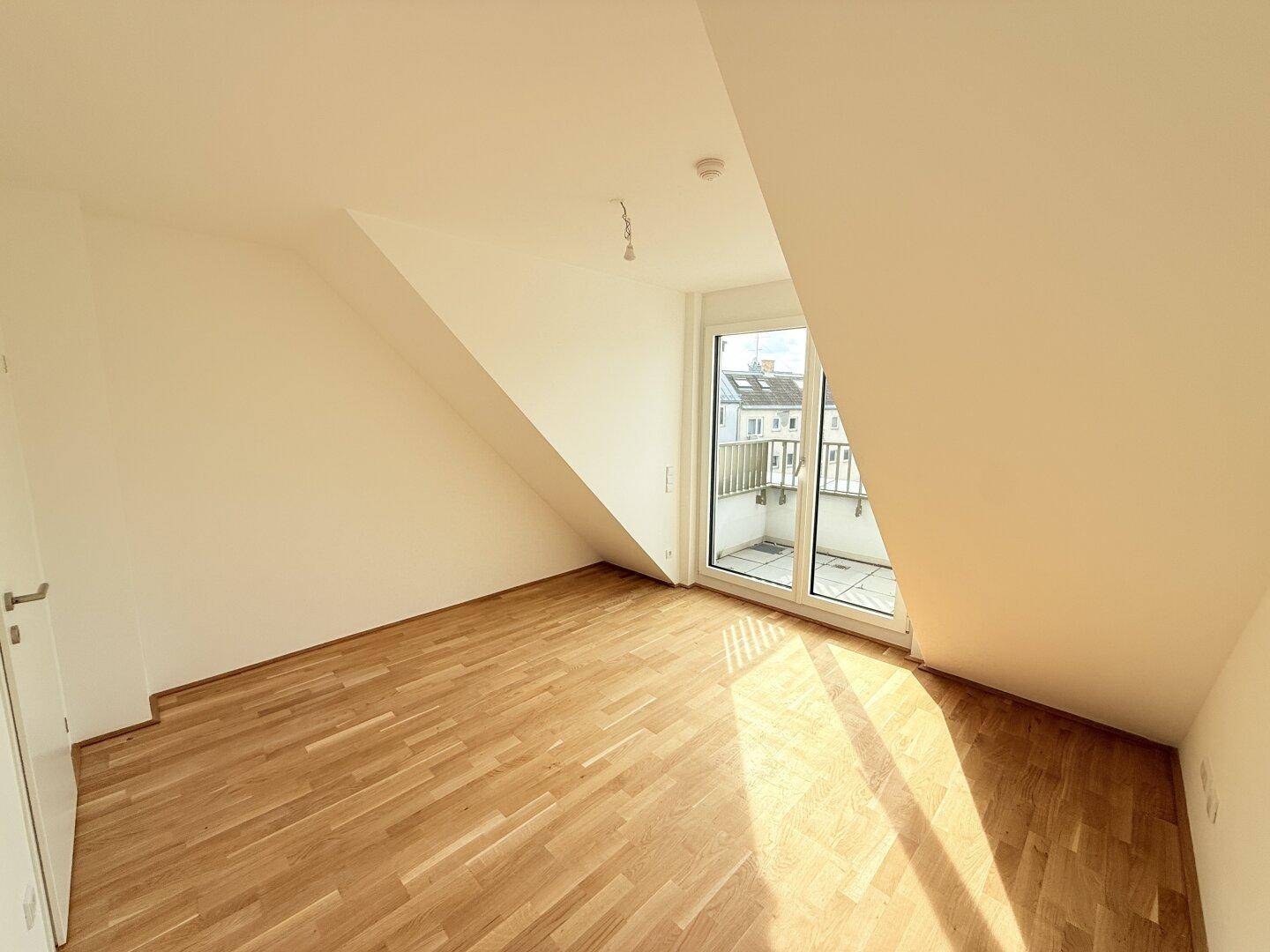 Lichtdurchflutetes Schlafzimmer mit Parkettboden und Balkonzugang, bietet eine angenehme Atmosphäre.