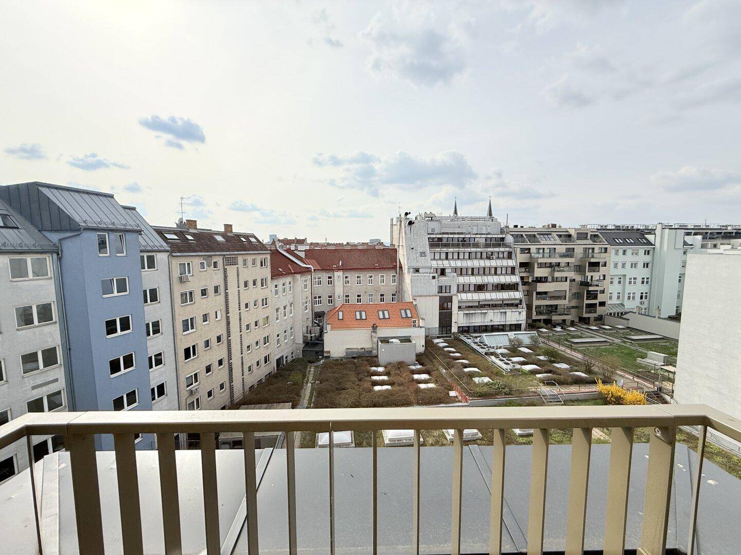 Balkon mit Metallgeländer und Fliesenboden, bietet einen weiten Blick über die Dächer der Stadt.