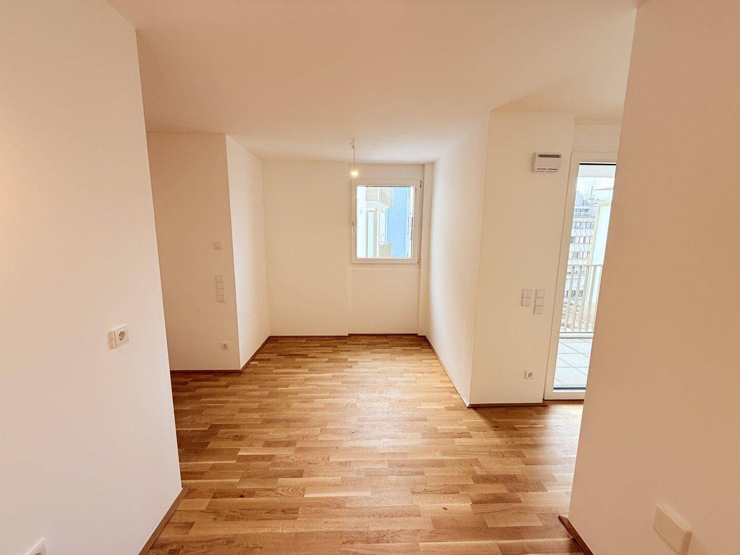 Heller Raum mit Parkettboden, Fenster und Zugang zu einem Außenbereich, der vielseitig nutzbar ist.