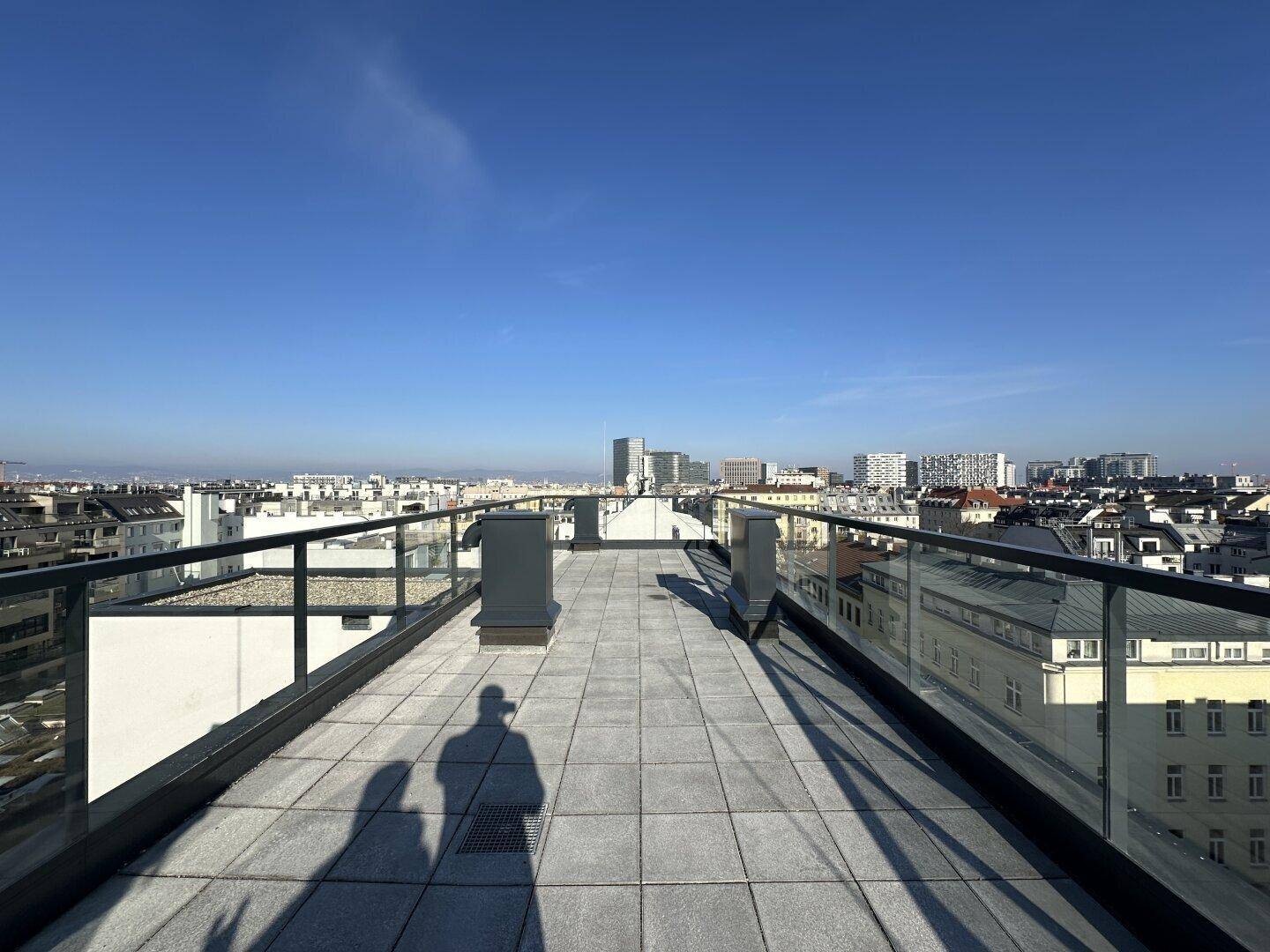 Sonnige Dachterrasse mit weitem Blick über die städtische Skyline.