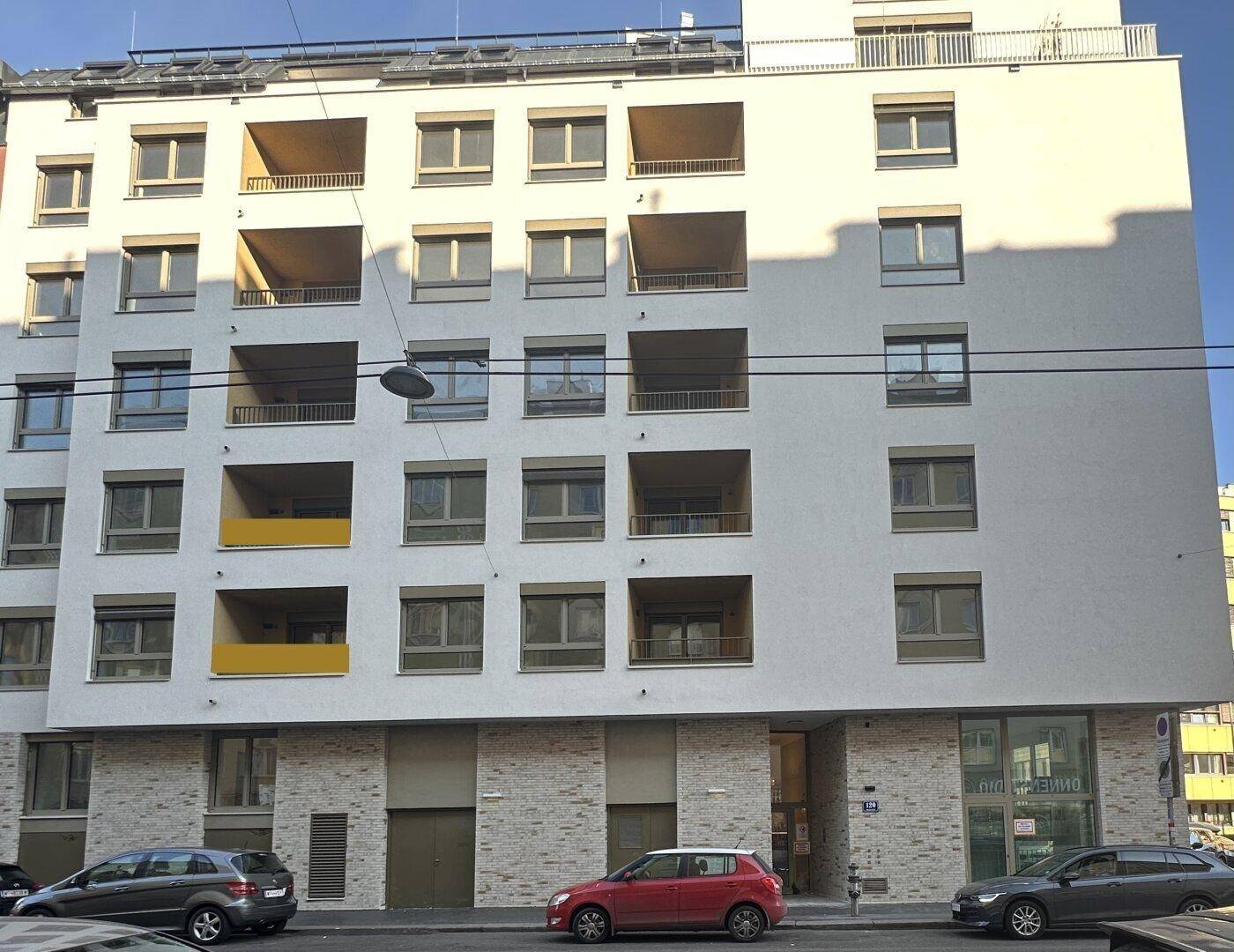 Moderne Wohngebäude-Fassade mit mehreren Balkonen und großen Fenstern.
