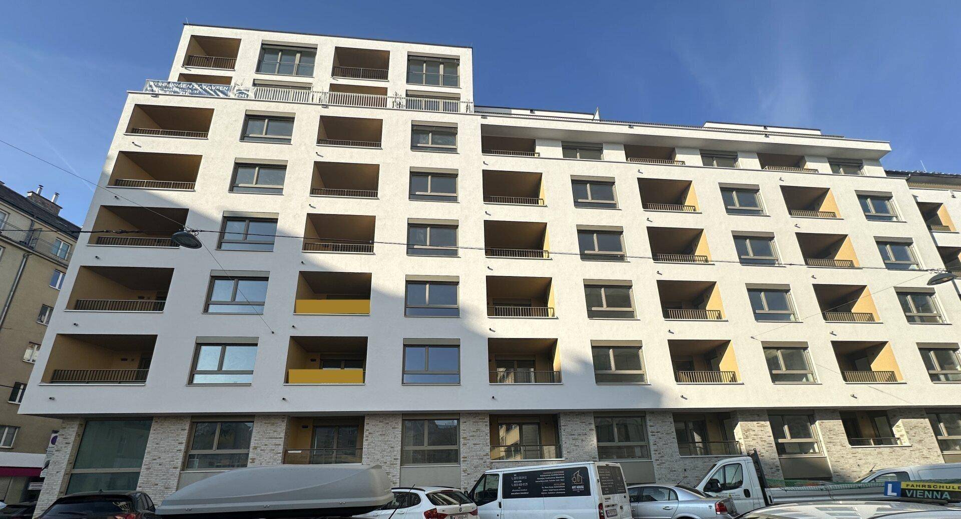 Ansicht der modernen Wohnhausfassade mit zahlreichen Balkonen und großen Fenstern.