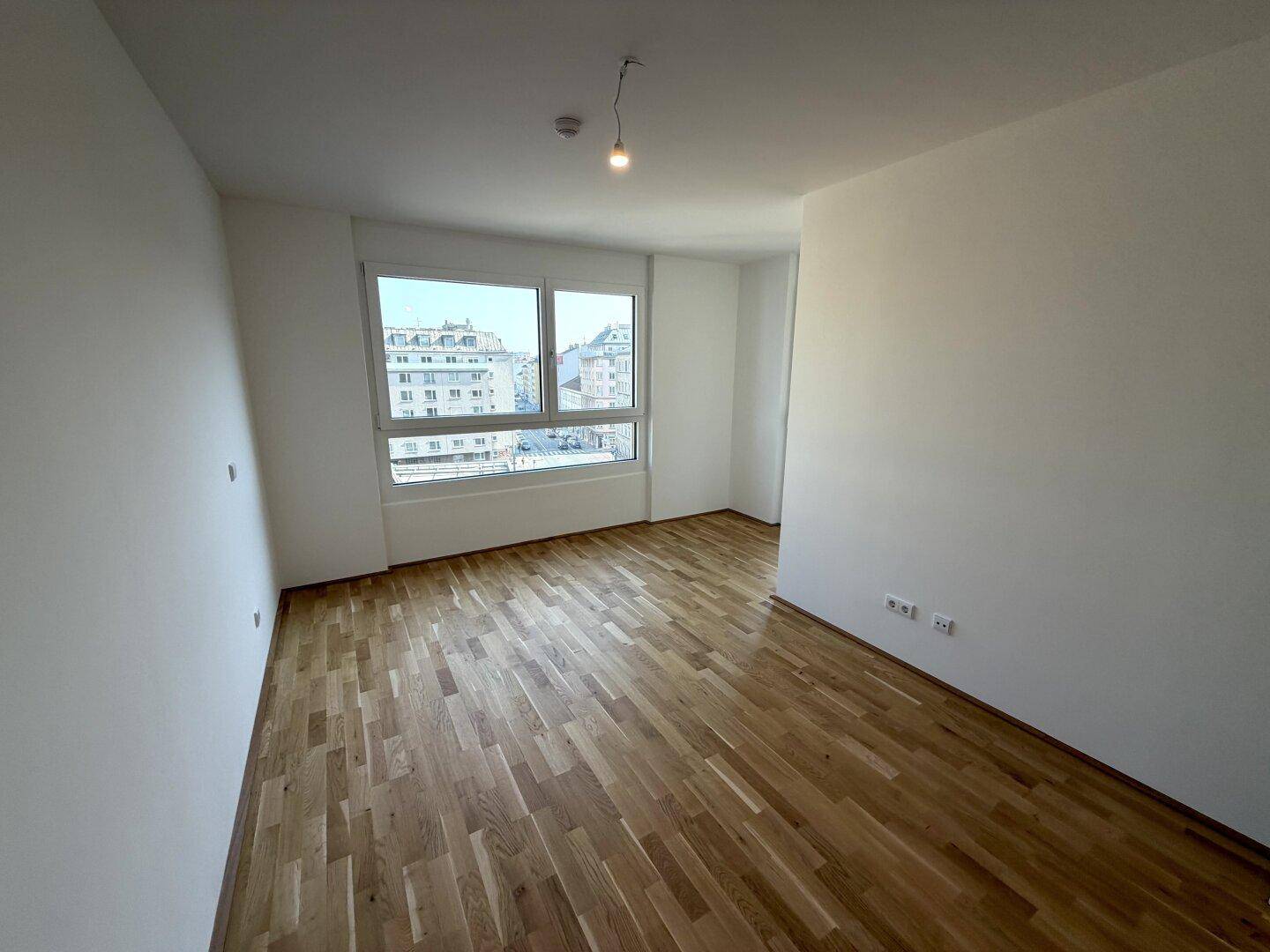 Lichtdurchfluteter Raum mit Parkettboden und weitem Blick über die Stadt.