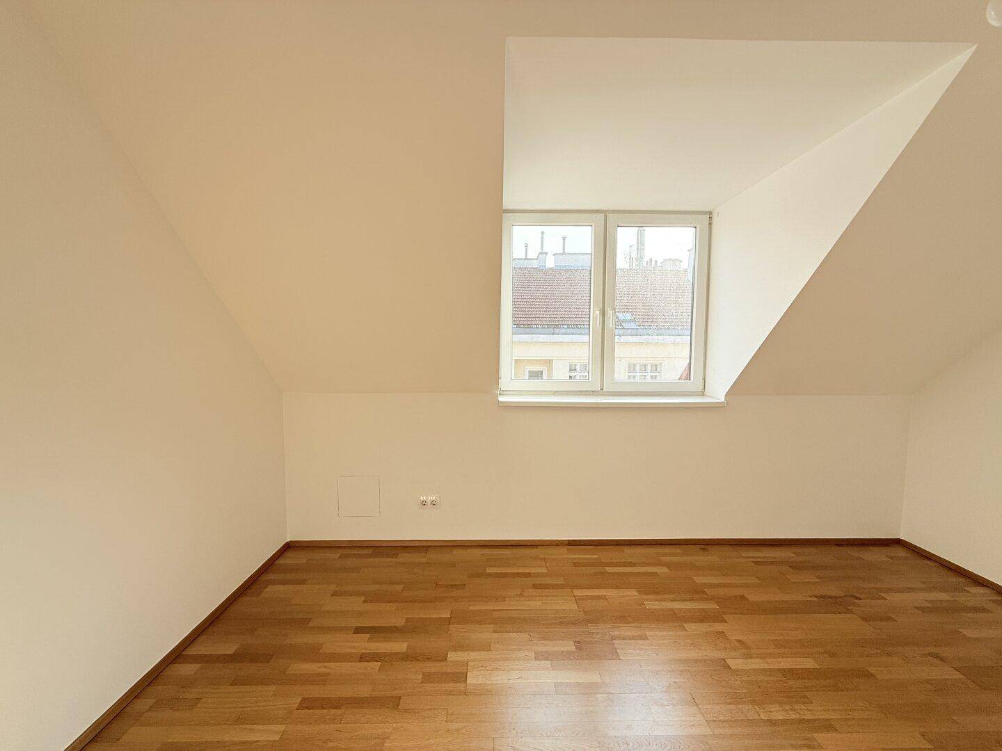 Geräumiges Zimmer mit Parkettboden und ausgeprägten Dachschrägen, bietet viel Tageslicht.