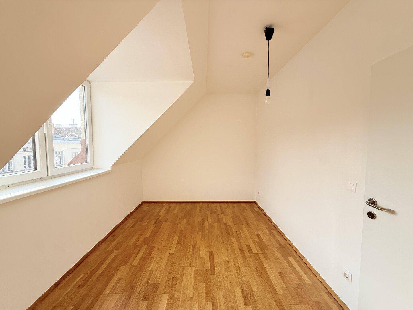 Helles Zimmer mit Parkettboden und Dachschräge, ideal als Schlaf- oder Arbeitszimmer.