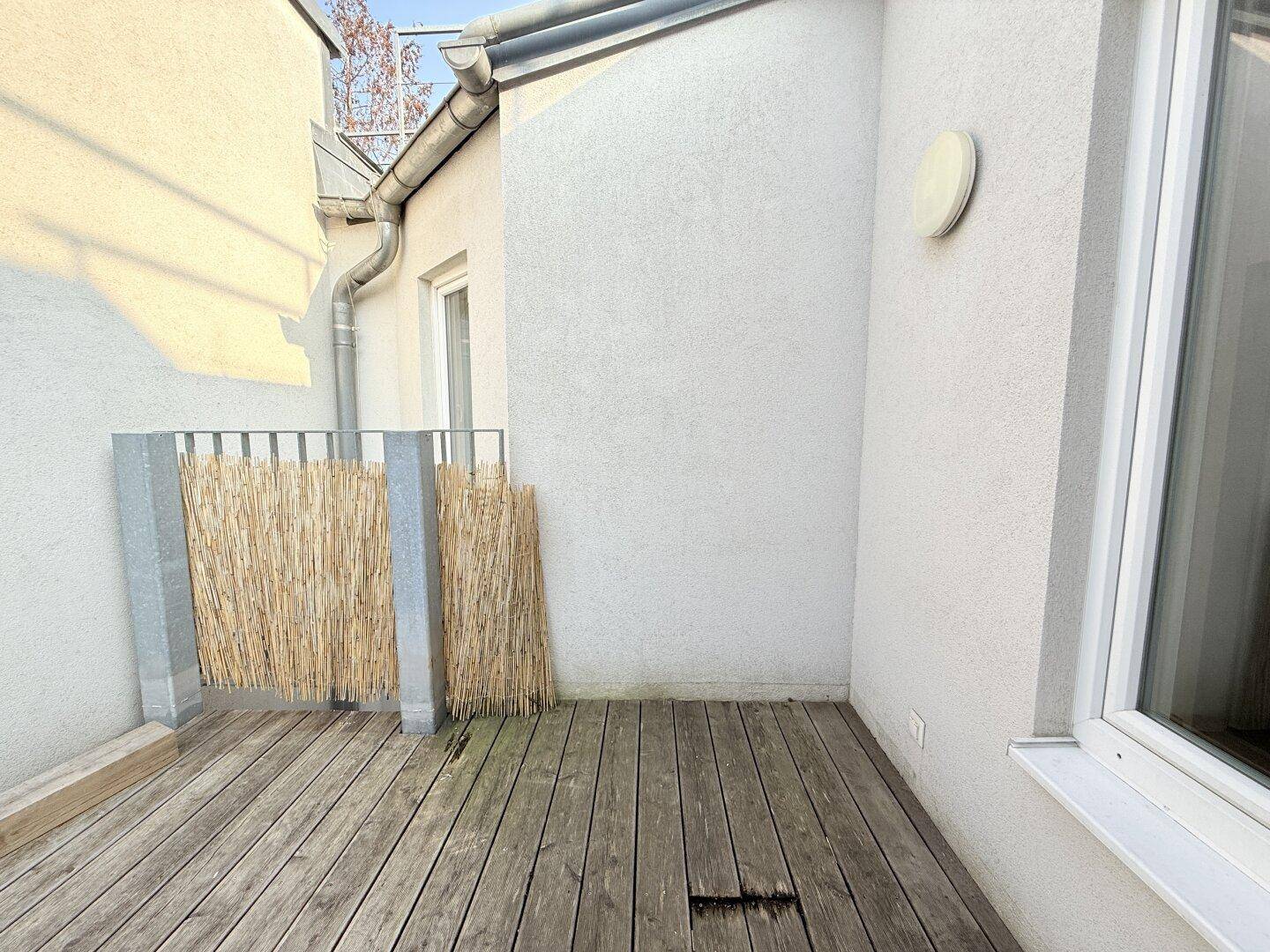 Gemütliche Terrassenecke mit Holzboden und Sichtschutz, ideal für private Momente im Freien.