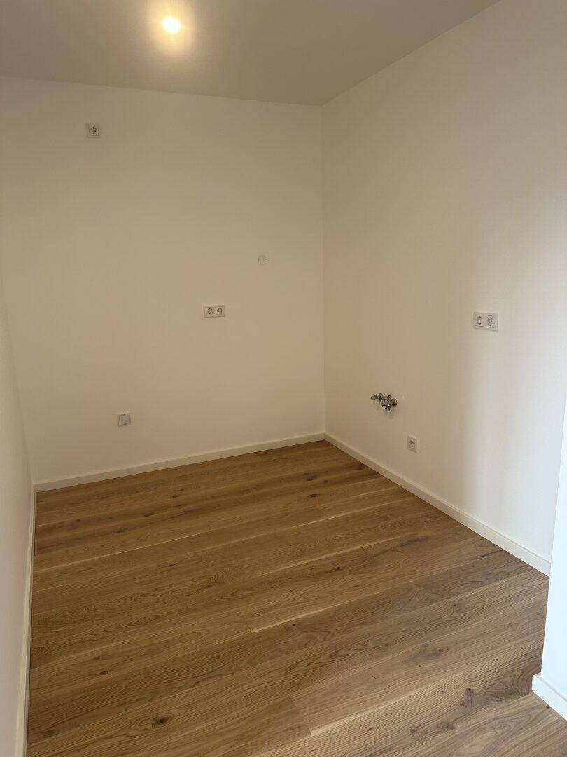 Leeres Zimmer mit Parkettboden und weißen Wänden, ideal als Schlaf- oder Arbeitszimmer.