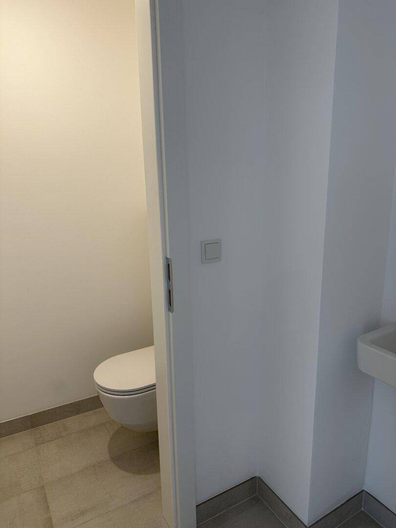 Modernes Gäste-WC mit wandhängender Toilette und kleinem Waschbecken in minimalistischem Design.
