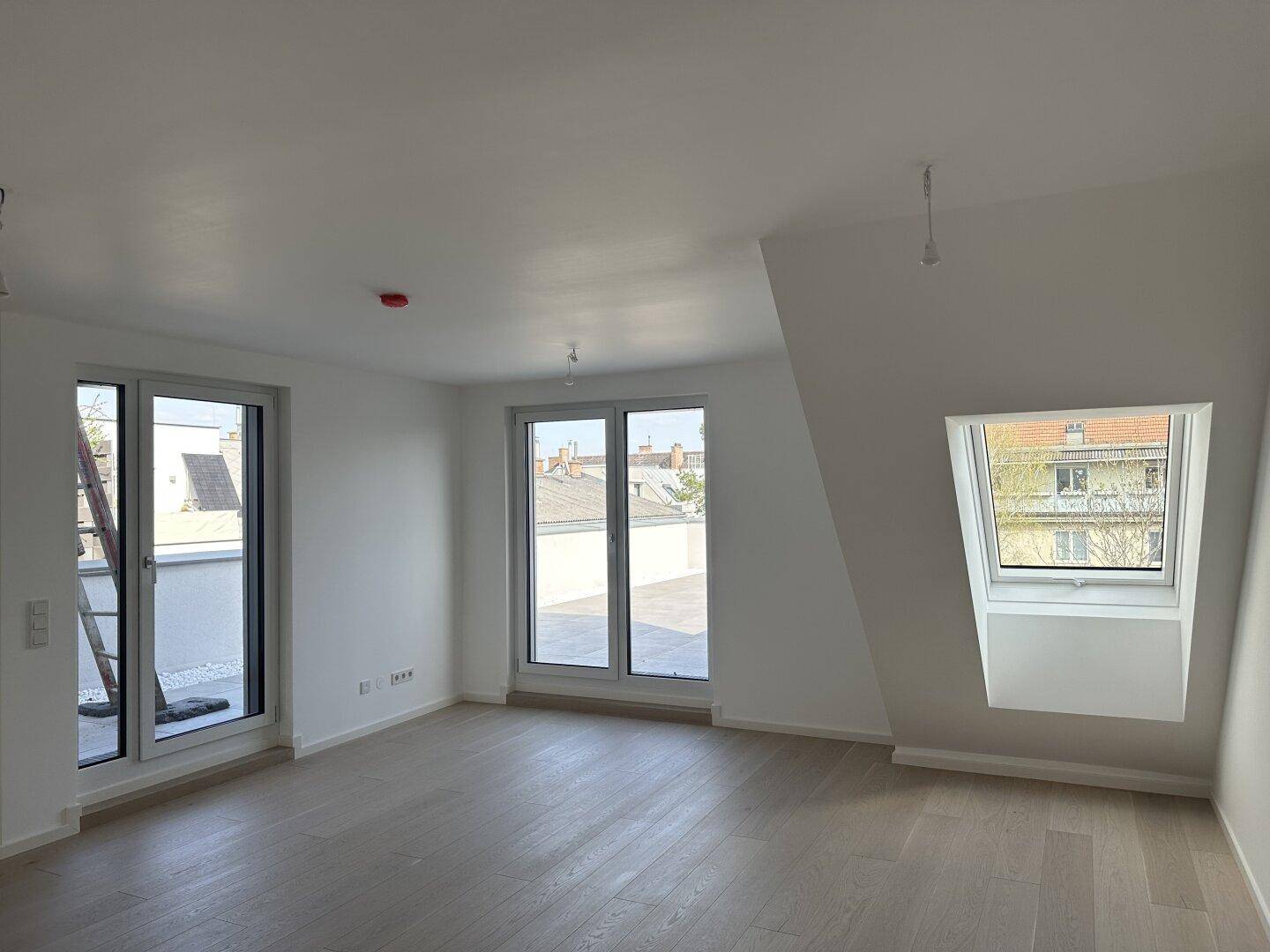 Geräumiger Wohnbereich im Dachgeschoss mit Zugang zur Terrasse und einem zusätzlichen Dachfenster.