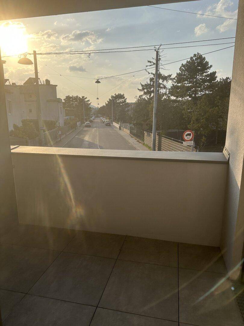 Balkon mit Blick auf die Straße und die umliegende Wohngegend bei Sonnenuntergang.