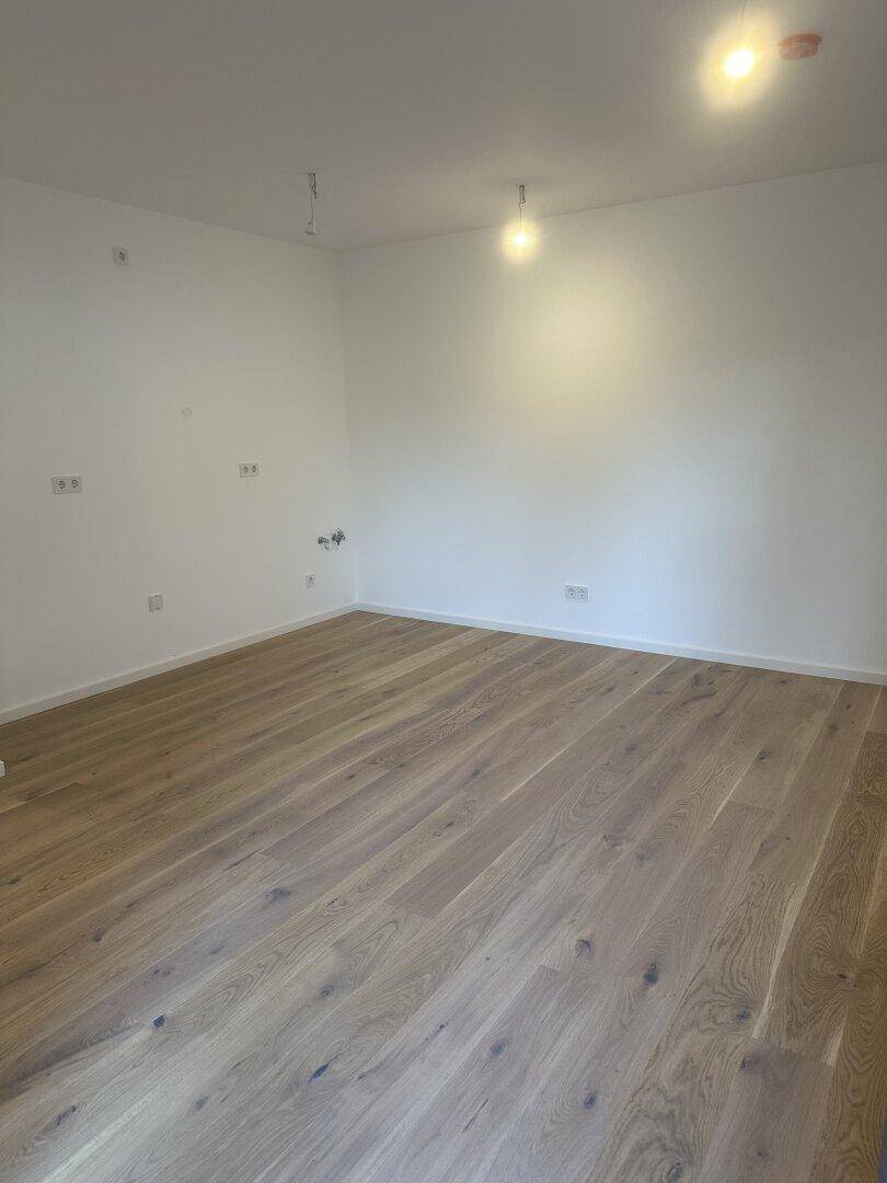 Heller Raum mit hochwertigem Holzboden und frisch gestrichenen Wänden, bereit zum Einzug.
