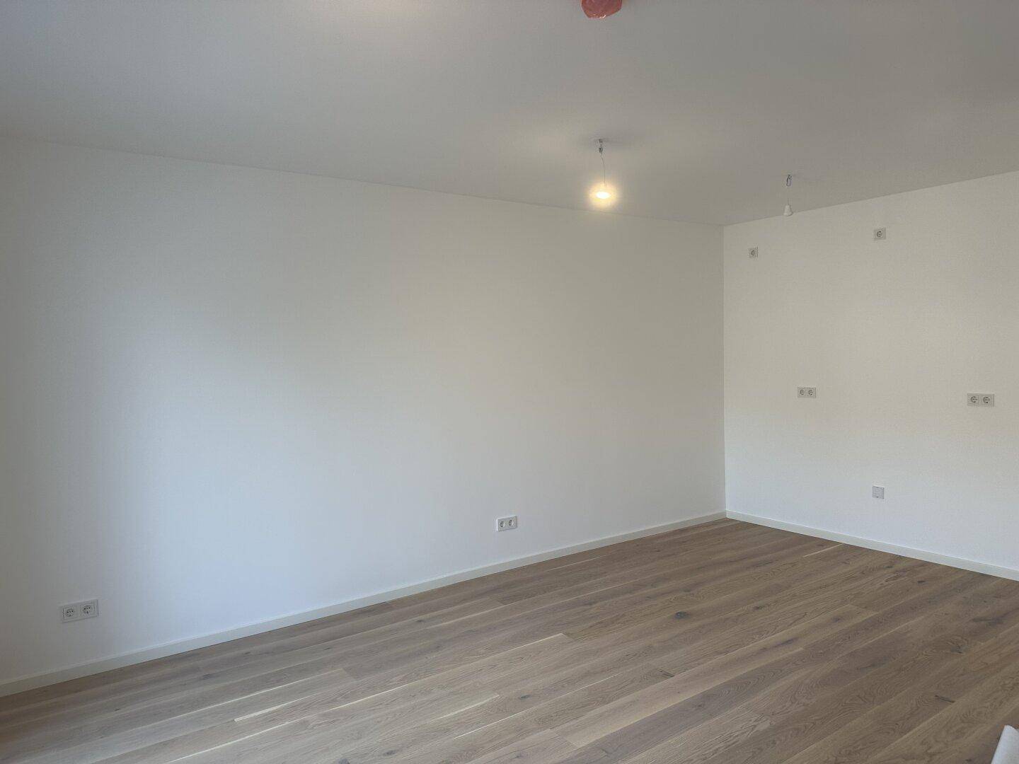 Geräumiges Zimmer mit hellem Holzboden und weißen Wänden, ideal für individuelle Gestaltung.