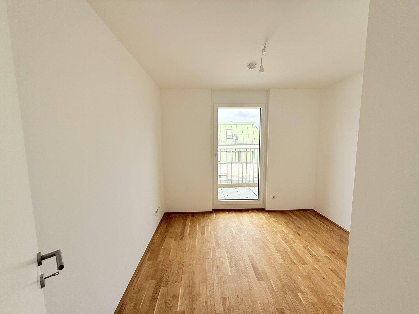 Helles Zimmer mit Parkettboden und Balkontür, ideal als Schlaf- oder Arbeitszimmer nutzbar.