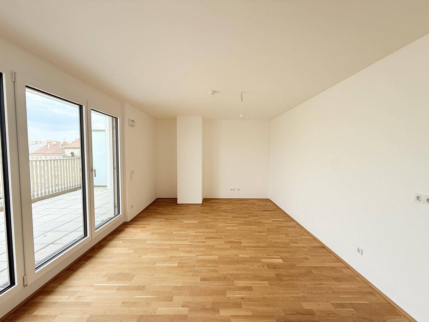 Weitläufiger Raum mit Parkettboden und großen Fenstern, bietet viel Licht und Flexibilität für die Gestaltung.