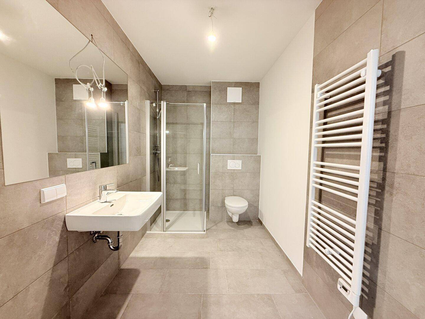 Modernes Badezimmer mit Dusche, Waschbecken und beheiztem Handtuchhalter, in neutralen Farben gehalten.