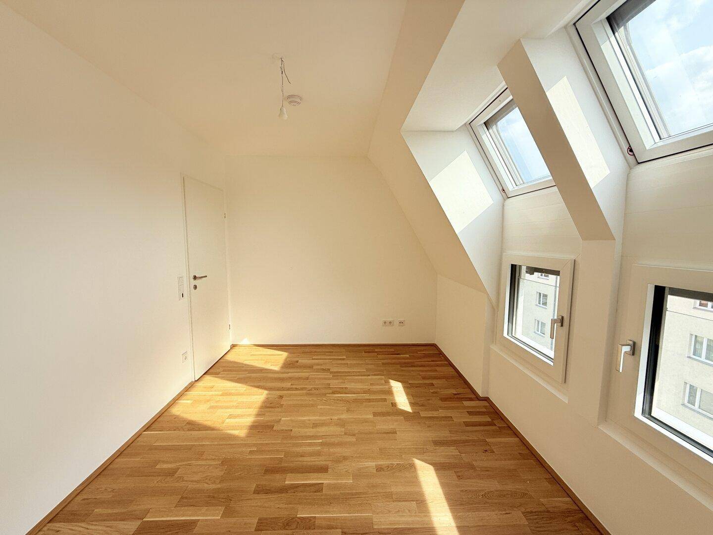 Geräumiges Schlafzimmer im Dachgeschoss mit Parkettboden und Dachfenstern, die viel Licht spenden.
