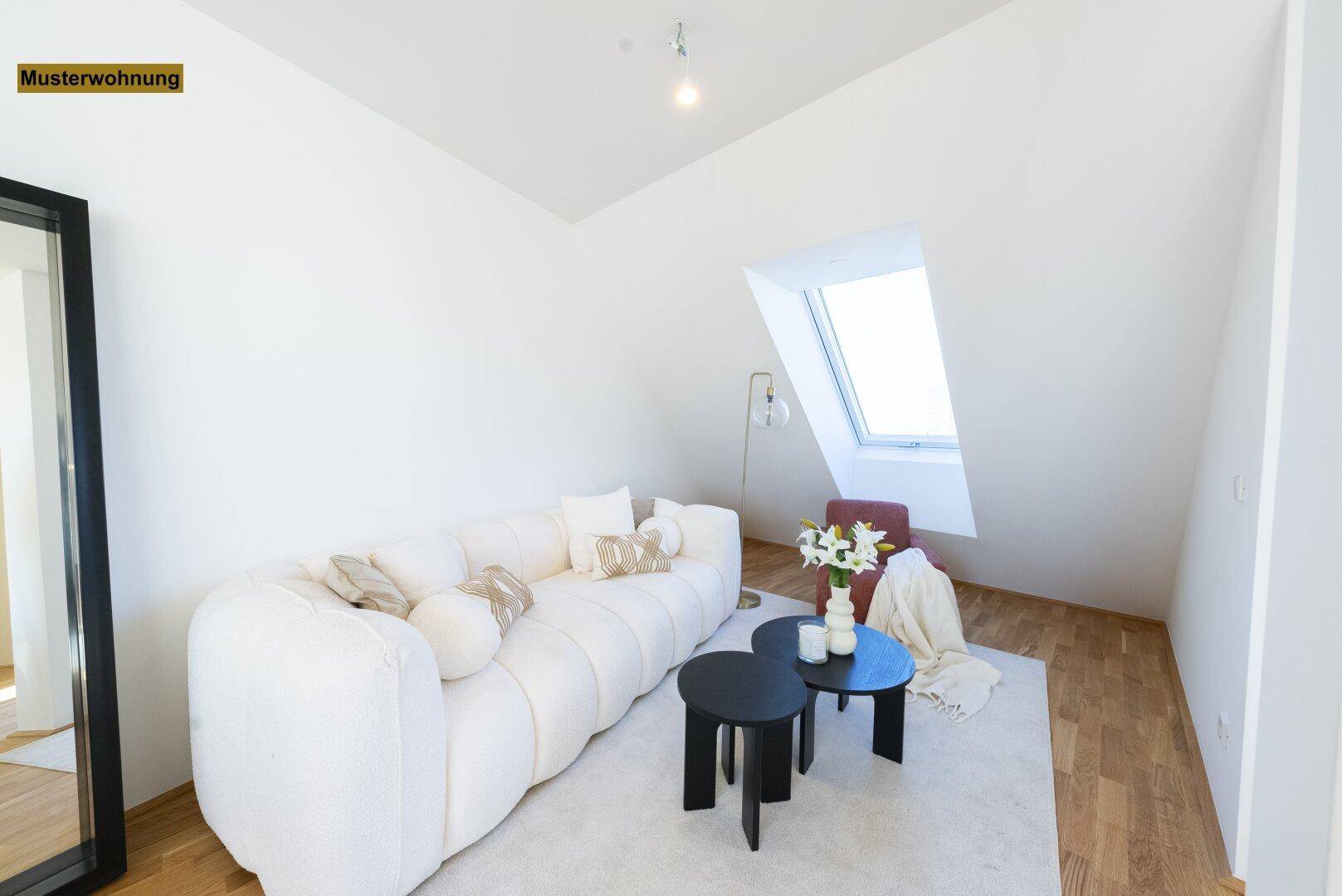 Gemütlicher Wohnbereich mit weißem Sofa, Couchtischen und Dachfenster.