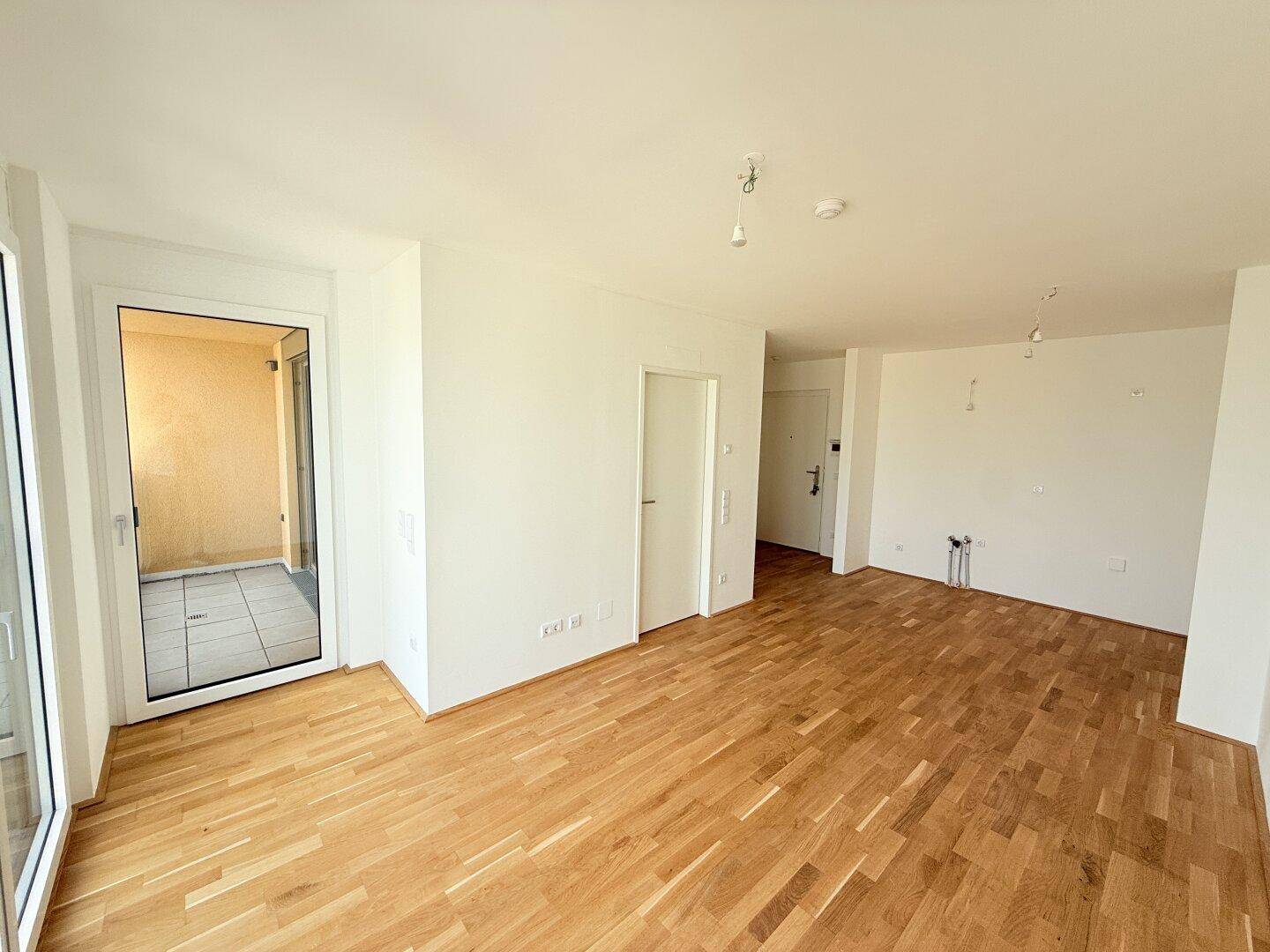 Heller Wohnbereich mit Holzboden und direktem Zugang zu einem Außenbereich.