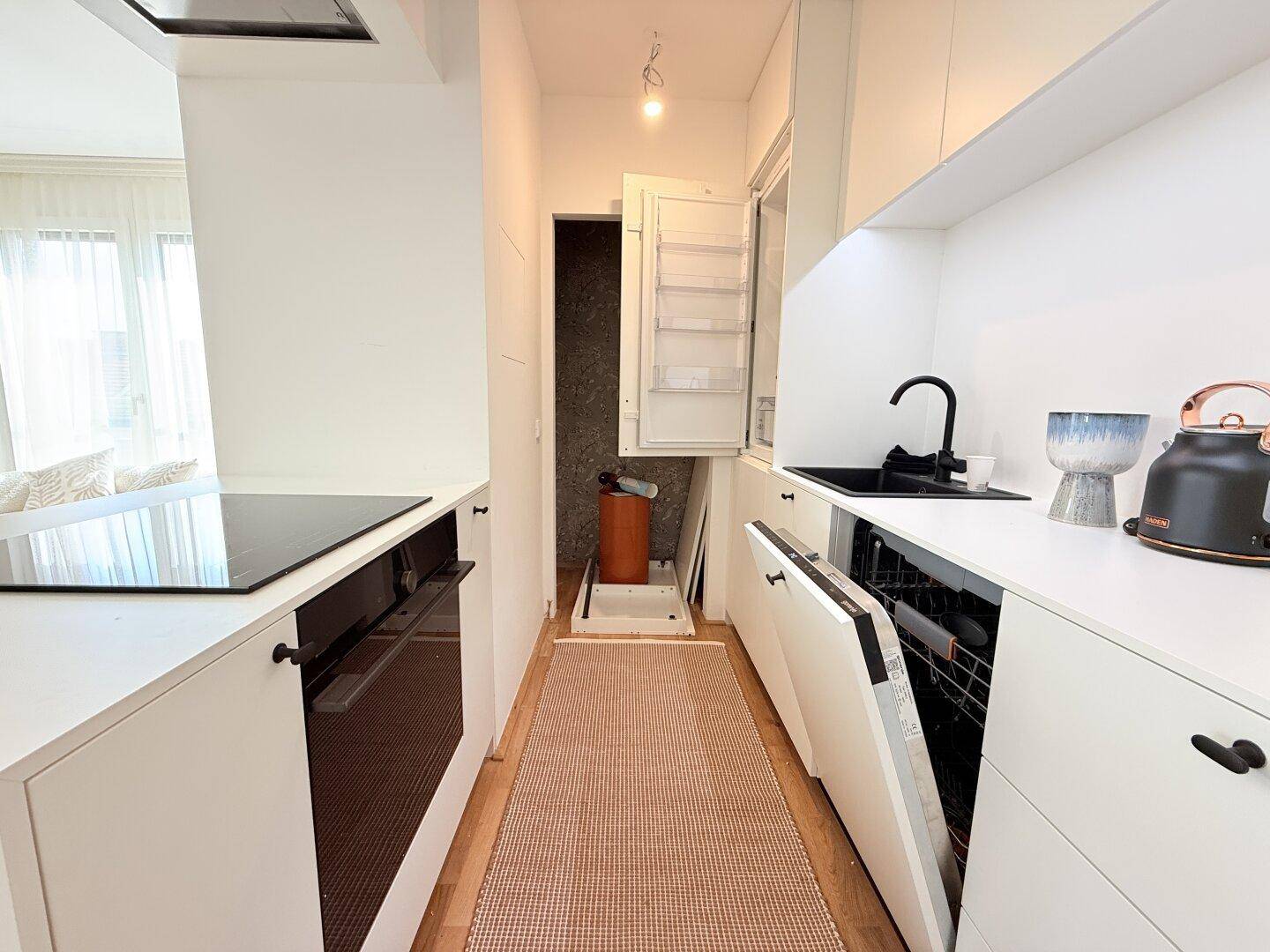 Moderne Küche mit weißen Schränken, Geschirrspüler und Kühlschrank.